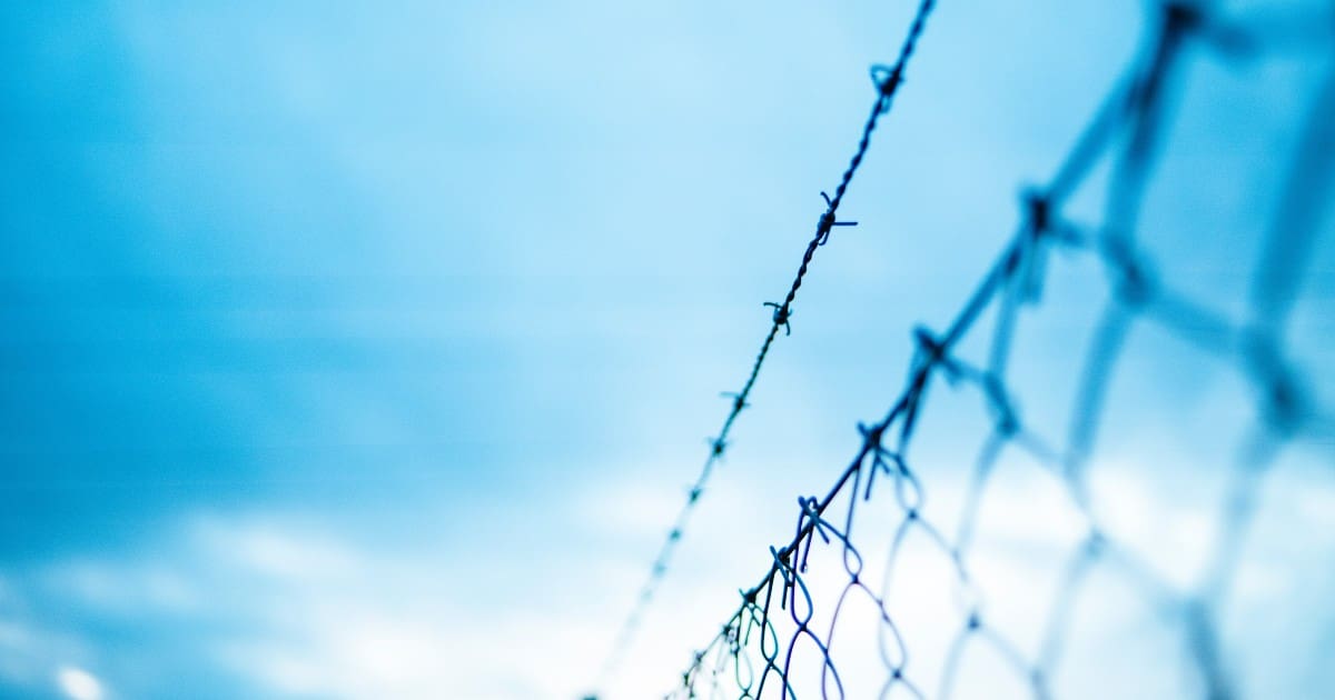 chainlink fence behind a blue cloudy sky