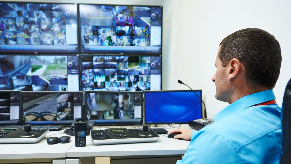 man watching computer screens with live security camera footage