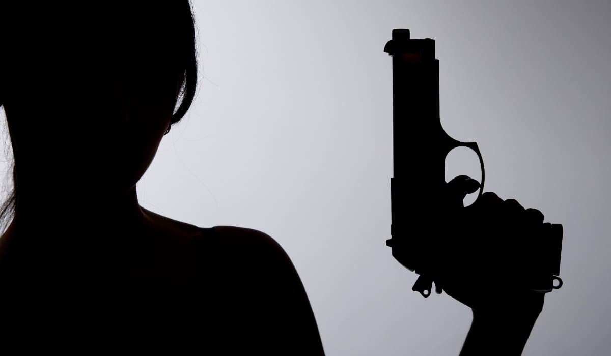 silhouette of a person holding a gun on a gray background