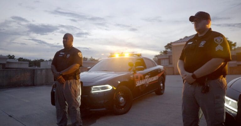 two silbar security guards standing in front of their patrol cars