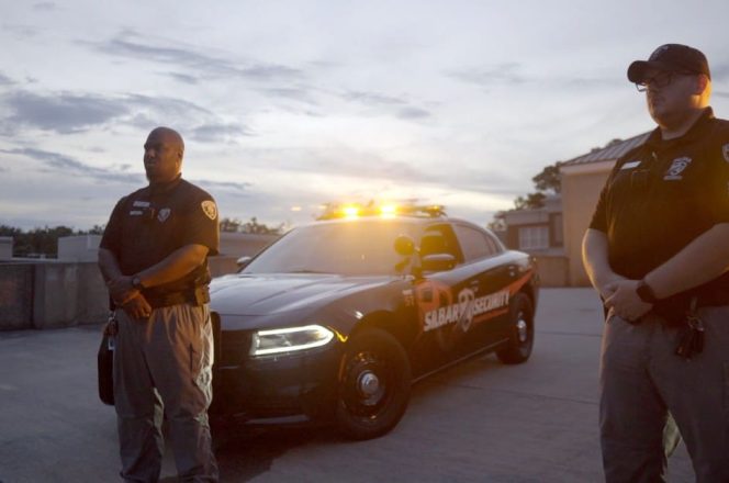 two silbar security guards standing in front of their patrol cars
